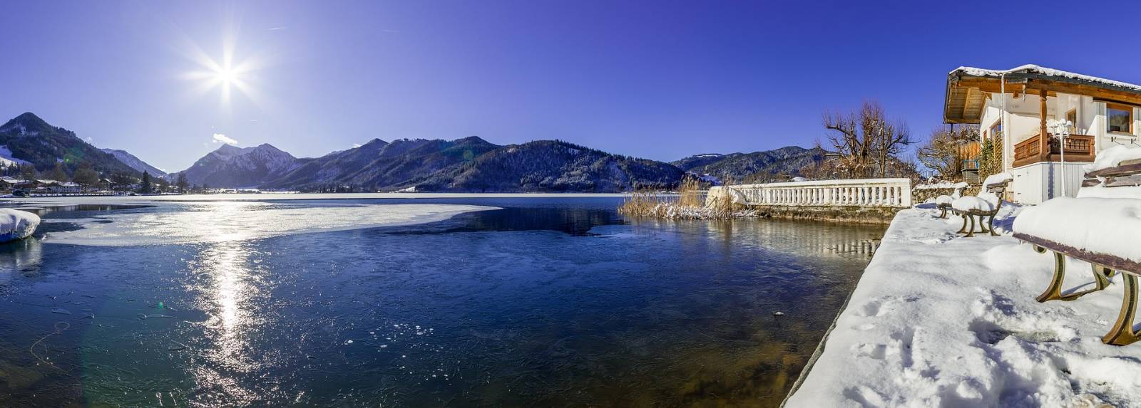 Der Schliersee im Winter, Sonne über der verschneiten Bergkette